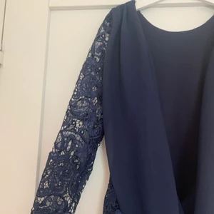 Marinblå spetsklänning m. öppen rygg - Supersnygg marinblå klänning i spets med öppen rygg. I bra skick och knappt använd, säljer pga att den inte passar mig. I storlek XS, ursprungligen från Nelly.