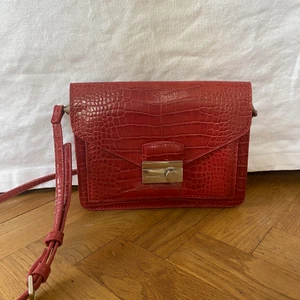 Axelbandsväska  - Säljer en röd axelbandsväska i bra skick. Två fack i väskan. Frakt tillkommer! 