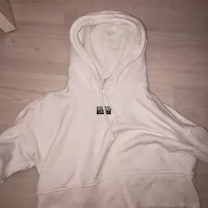 En croppad vit hoodie med luva från adidas. Med svarta detaljer,  Storlek S. Använd några gånger men nästan nyskick. 