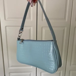 Baguette väska - En fin ljusblå väska, som passar perfekt nu till sommaren. Den har ett kort band, samt endast ett stort fack. Jag säljer den för 100kr + frakt