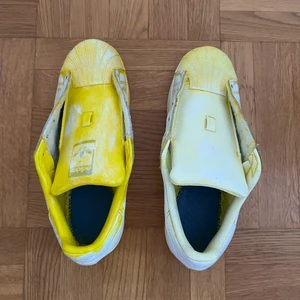 Adidas superstar - Ett par adidas superstars jag har målat gula med ”skofärg”, men sedan ångrat mig och försökt ta bort färgen med aceton. Snörena är borttagna. Det är använda utomhus 1 gång i högst 30 min. Om ni vill prova att måla på skor kan dessa vara ett perfekt ”testpar”, det är ju dessutom rättså ”rena” eftersom de knappt använts utomhus. (Jag har kvar gul färg och ”finisher” från Angelus, som man kan få med för 50 kr extra). KÖPAREN STÅR FÖR FRAKT, skickar spårtbart PostNord paket.