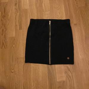 En svart kjol med en dragkedja som ej går att använda. Den är i storlek 158-164 knappt använd.