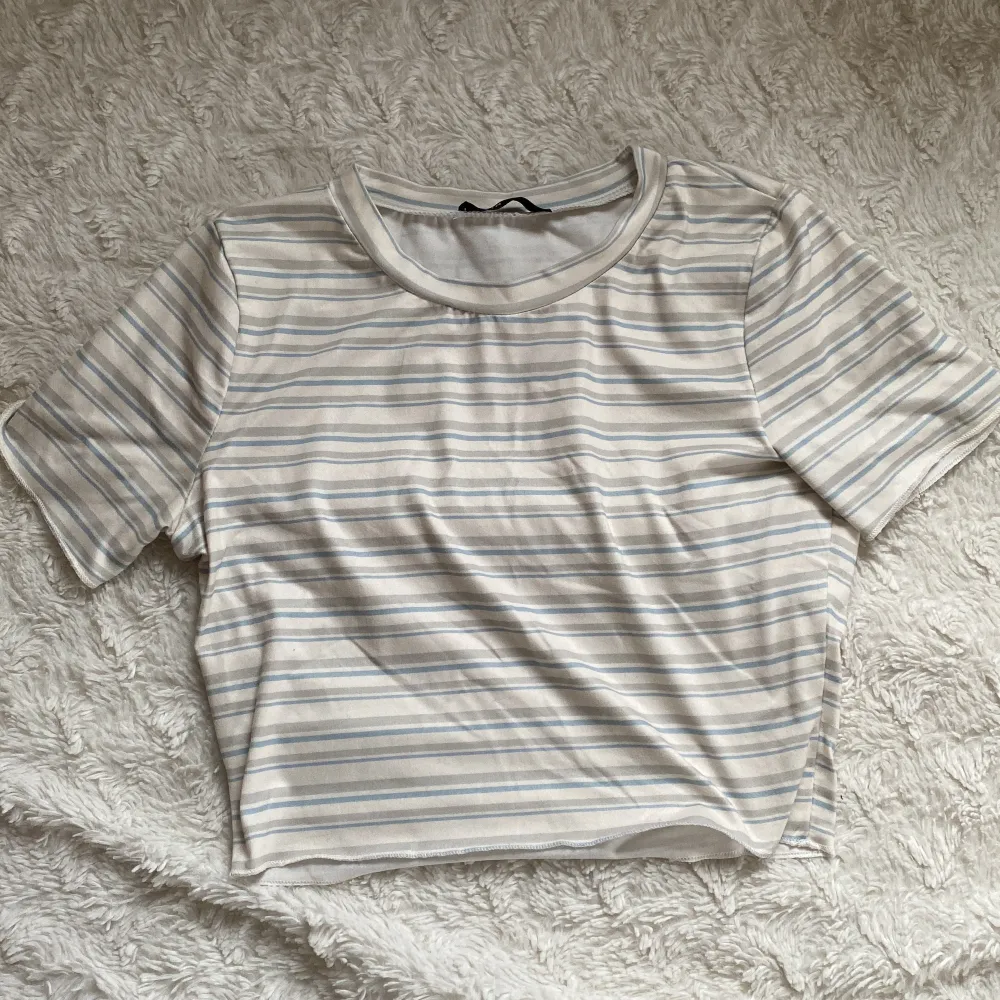 Supersöt randig t-shirt från Shein. Ränderna är i färgerna ljusblått, beigt och grå. Toppen är en aning croppad.. T-shirts.