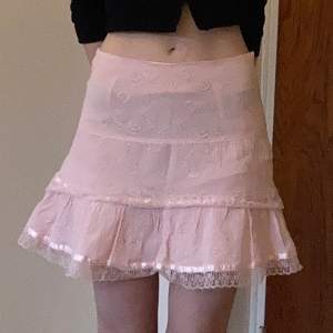 Söt rosa kjol med volanger. Har klippt den vilket märks på underkjolen men inget man kan se när kjolen väl är på. Något genomskinlig. 