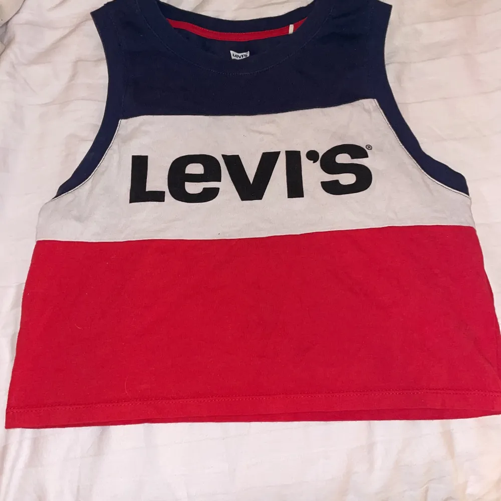 En blå vit och röd tröja med texten ”Levi’s”. T-shirts.