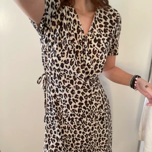 Omlottklänning - En fin omlottklänning i leopardmönster! Endast använd 1 gång men är avklippt längst ner i längden! Men i väldigt bra skick! Justerbar så passar XS-L!