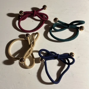 Tofsar / gummiband - Fyra tofsar / gummiband som man gör rosett med, guldiga bollar, marinblå, vinröd, beige och grön. Alla för 30kr. Frakt 13kr💕