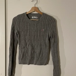Grå kabelstickad tröja från Hollister - Grå kabelstickad tröja från Hollister. Tröjan är i storlek XS men passar också S. Kolla gärna in mina andra annonser!  Titta noga på alla bilder och skicka meddelande vid frågor. Jag ansvarar inte för postens slarv. Sam fraktar gärna flera varor tillsammans.