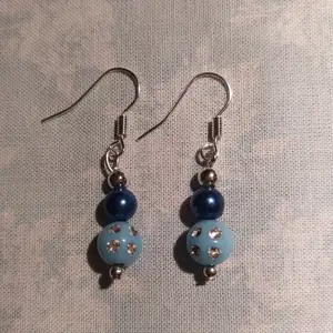 Ett par hemmagjorda örhängen med olika blå/silvriga pärlor. Krokarna är nickelfria, oanvända. 