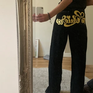 Svarta jeans - Svarta jeans med synliga sömmar och ”te quiero” skrivet på rumpan i gult 😍 finns inga lappar men skulle säga att dom är en M/ 38-40
