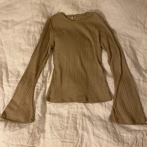 Ribbad topp med trumpetärmar - Oanvänd ribbad topp från Nelly. Den var tyvärr för liten för mig, men såå snygg. Ärmarna går ut vid handleden men annars sitter den tight på kroppen. Perfekt skick