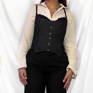 Pinstripe Korsett - Snygg pinstripe/kritstrecksrandig korsett med rhinestones på axelbanden. Fästet är bak och det finns dekorativa knappar fram. Äkta korsett med boning.   Ingen lapp på plagget men passar storlek 38-40, B-C kupa.  Tecken på tidigare användning men i fint skick överlag.  Kunden står för frakt som inte ingår i priset och paket skickas så fort som möjligt.  Meddela om du har fler frågor eller vill se fler bilder.