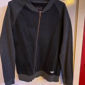 Tröja med dragkedja, strl M - En basic grå och svart tröja med dragkedja i storlek M, haft den en litet tag så lite sliten kan den vara men i det stora hela är skicket fortfarande bra.