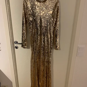 Långklänning i guld - Den fjärde är en långklänning från Nellys Balkollektion. Inköpt för 1200 kronor. Täckt helt av paljetter i guld med öppen rygg.  Stl: 40. Pris 300 kronor. 