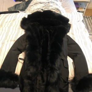 Svart Parka jacka med äkta päls.  - Denna parka jacka är varm och är köpt från borninstockholm.se. För cirka 1 år sedan. Använd 1 gång och är helt fläckfri utan några skador! Nyskick. Äkta päls. Jackan är i storlek - 36/S.