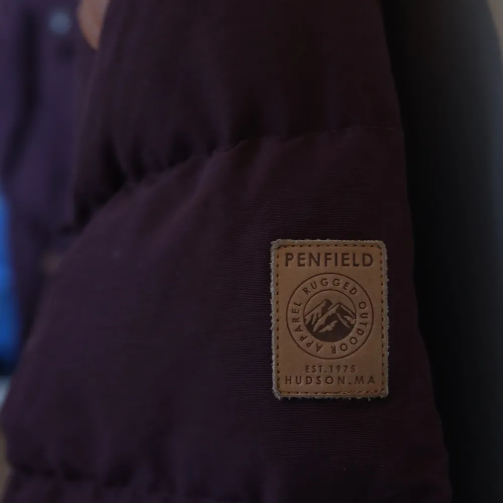 Vinröd dunjacka från Penfield i trailerwear-stil. Läderdetaljer i beige.  Den är mycket sparsamt använd men har fått en liten skavank på vänster axel. . Jackor.