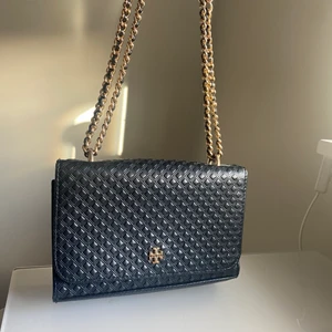 Tory Burch mini bag - Säljer denna svarta Tory Burch mini bag med guldiga detaljer. Är använda men fortfarande i gott skick! Man kan välja att ha det som en crossbody bag eller korta ner kedjan och ha den på ena axeln. Finns även små kort fack inne i väskan. Säljer den för 250kr😊