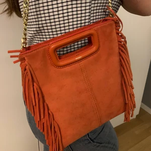 Maje väska - Säljer min majeväska då den inte kommer till användning tyvärr. Köpt sommaren 2019 i en Maje butik. Inte använt så mycket så därför i bra skikt. Färgen kommer typ inte fram så bra på bilderna på Plick, men den är klar orange. KAN TÄNKA MIG ATT BYTA!!