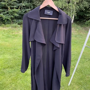 Svart trenchcoat storlek XS - Säljer en snygg svart trenchcoat från BikBok. Har ett svart skärp man kan knyta runt midjan tillbehörande. Aldrig använd. Utgångspris 100kr, frakt ingår ej.