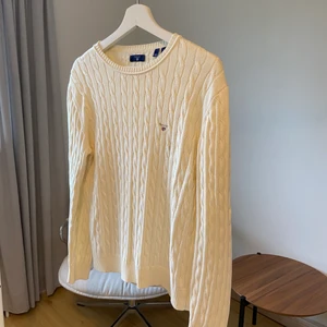Gant tröja - En kabelstickad tröja från Gant. Den är krämvit/sandvit i färgen. Tröjan är 170 i storleken vilket motsvarar en small. Säljs pga att den tyvärr inte kommer till användning längre. I övrigt är tröjan lite använd och i bra skick!