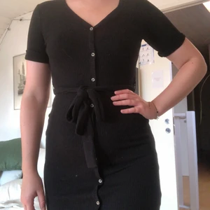 Jätteskön klänning - Svart klänning med knappar, slits och bälte från Lindex. Är i jättefint skick och endast använd 2 gånger. Storlek S (men passar mig i M och säker på att den funkar för L också).🥰
