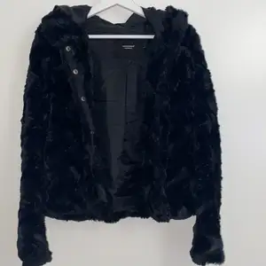 En svart lurvig jacka med luva, knappar och fickor från vero moda i storlek s