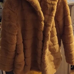 Fluffig jacka senapsgul ca strl L/XL - blandning mellan brunt och senapsgul,jätte härlig färg! fickor,dolda knappar och en riktigt stor luva. passar nog en L bäst