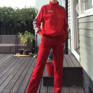 En röd track suit i gott skick och skönt material. Slutar vid fotknölarna på mig som är 170cm. Säljer båda delarna tillsammans