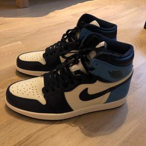 Ett par Nike Jordan 1 High i färgen Obsidian. Är i storleken 46 men sitter som en 45. Bara provade, annars helt oanvända och kommer i original lådan. Buda i kommentarerna, direkt köp vid 2 000kr.