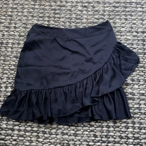 Volangkjol - Mörkblå volangkjol. Köpt i fel storlek. Helt oanvänd, knapp på baksidan fattas dock ( finns dragkedja man kan använda istället) 