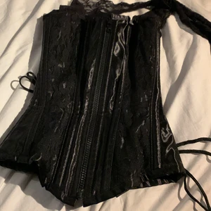 Korsett - Svart korsett från shock, bara testad i affären sedan har den legat i garderoben vill bli av med den!! Köpt för 600kr är jättefin med en tröja under eller utan någon på sommarn och lätt att ta på sig. Passar mig som har xa/s. Överbyst. Skriv om ni har fler frågor 