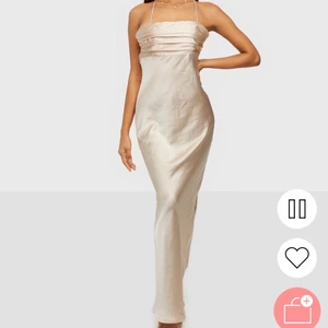 Beige satin klänning - Beige satin klänning från Nelly! Säljer med prislapp kvar då jag inte fått någon användning för den. Slutsåld på hemsidan🥰