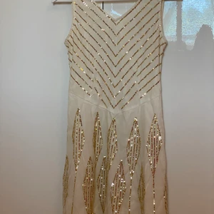 Cremevit chiffong klänning med guld paljetter - Cremevit chiffong klänning med guld paljetter från Cubus i storlek 36. Använt en gång