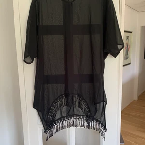 Strand klänning  - En svart stransklänning men gulliga tofsar längst ner. Bra skick inte använt så mycket pga har så många 