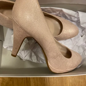 Rosa-glittriga Klackskor - Pumps/klackskor i rosa-glittrig färg. Endast använt en gång, sä de är i nyskick. Från ett märke som heter Catwalk. Storlek 38. 