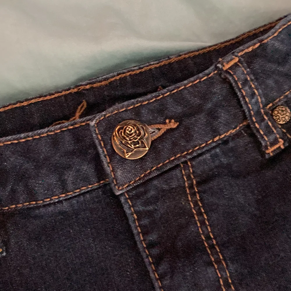  mörk blåa men en rosen knapp och detaljer på bak fickorna. Jeans & Byxor.
