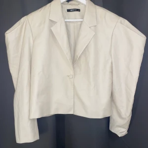 Kroppad kavaj  - Kroppad väldigt fin kavaj med puffiga axlar. Beige. Strl 34.   Kan mötas upp i Stockholm. Pris kan diskuteras vid snabb affär. 