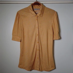 Retroblus - Gul, mönstrad blus med kort är. Mjukt och lent material. Knäpps med knappar, storlek M🌱