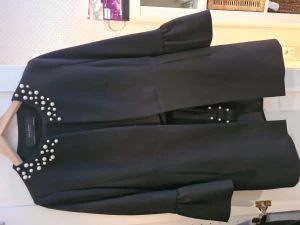 Kostym.  - Lång jacka med volangärm pärlemorpärlor i halsringning. Culottebyxor. 