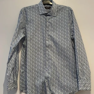 Sommar skjorta  - Sommar skjorta i blommigt mönster, ljus. Från dressman och alldrig använd. 