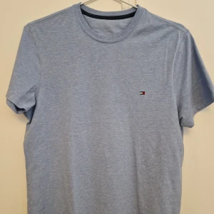 Tommy Hilfiger T-shirt ljusblå - Köpt i USA. Den är i amerikansk storlek xs, vilket sitter mer som en vanlig S. Jag som väger 75 kg o är 175 kan fortfarande ha den. Den är använd, men enda riktiga tecknet på slitage är att texten i nacken nästen försvunnit. Buda på!
