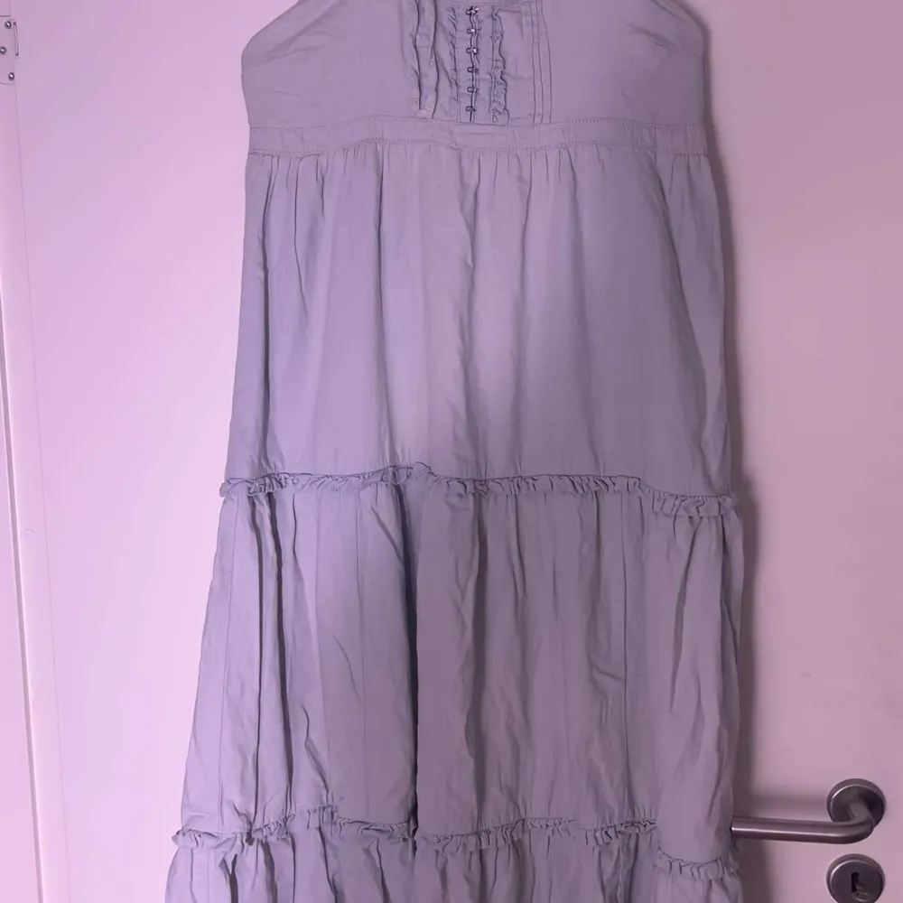 Långklänning med snöre runt nacken tunnt denim tyg . Mekot.