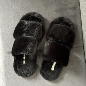 Tofflor  - Säljer ett par svarta fluffiga tofflor från HM, dom är i helt normalt skick. Använd endast få gånger. Säljer på grund av att dom inte kommer till användning 