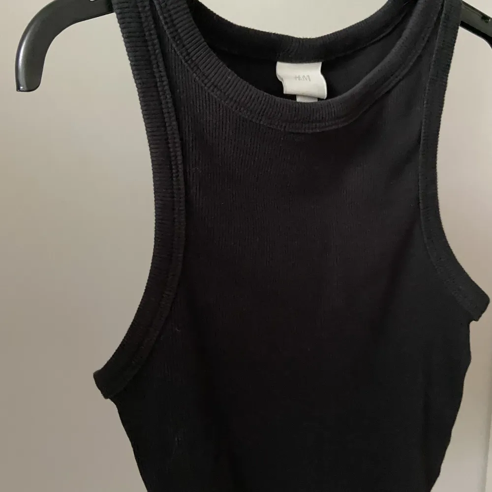 En svart topp ifrån H&M som bara används få gånger. Ganska kort, går ungefär ner under naveln.. Yläosat.