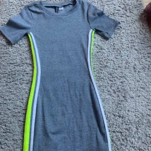 H&M  klänning strl xxs - Säljer en H&M klänning i storlek xxs som är grå med vita och neongröna linjer på sidan. Klänning är använd få antal gånger och den är som ny. Köparen står för frakten själv om köparen inte kan hämta ut klänningen i Oxie. Betalning sker via swish
