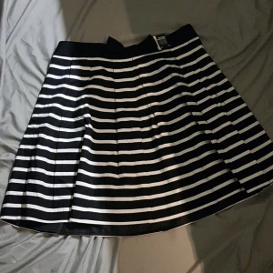 Svartvit kjol i taft  - Jättefin kjol i svartvit taft. Aldrig använt den så helt nyskick! Strl 46/48. Har svart rosett famtill i midjan.