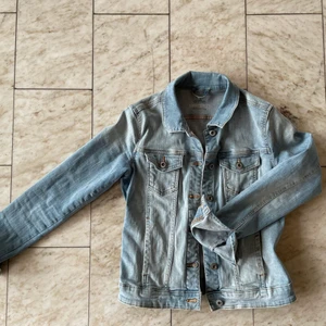 Jättefin ljusblå jeansjacka från Esprit - Jättefin jeansjacka från jeansmärket av Esprit som passar perfekt nu till sommaren. Jackan sitter åt och har fickor på in och utsidan. Plagget är knappt använd och ser ut som ny. Vid interesse hör gärna av dig.
