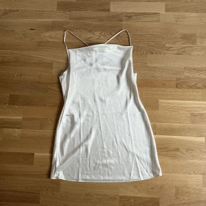 Klänning - Miniklänning i satin med öppen rygg och banddetalj som går över ryggen. Väldigt bra skick.