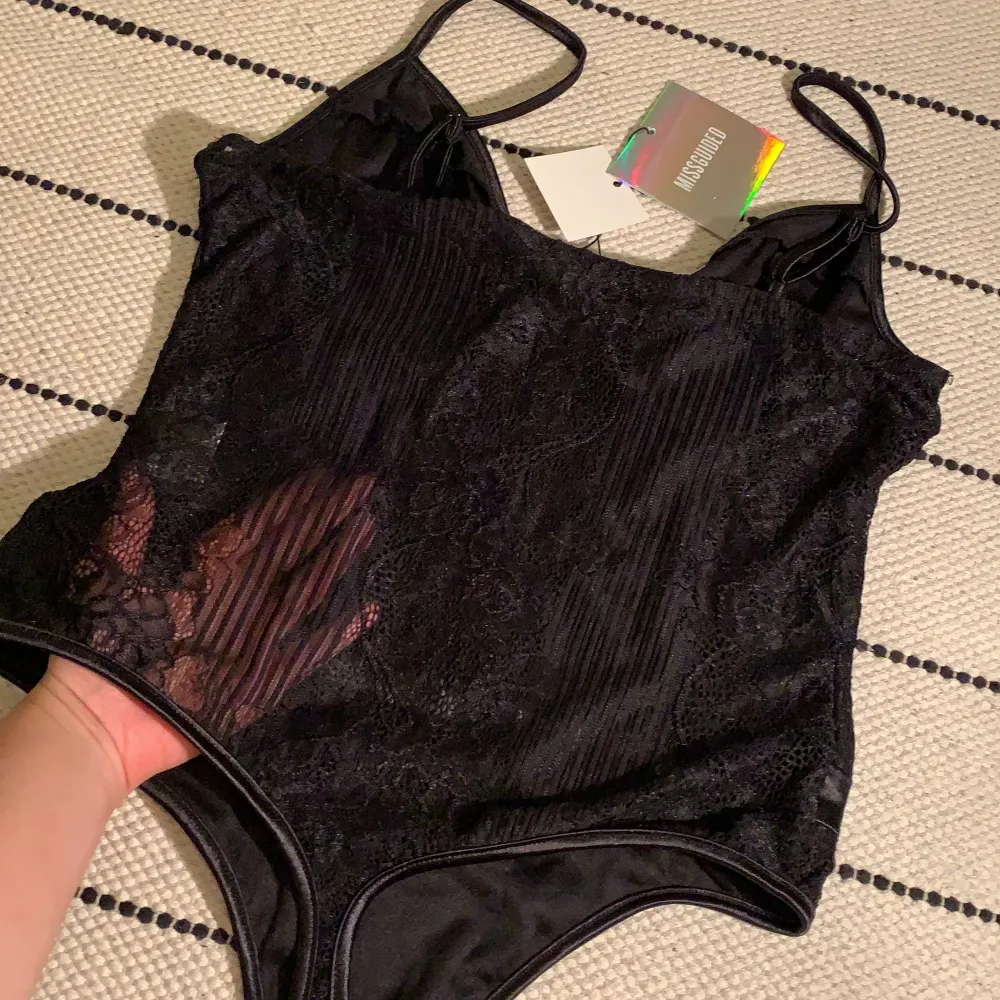 Svart spetsbody från Missguided, storlek eu 38. Korsettliknande men inte lika ”fast” och bygellös. Baksidan av bodyn är i spets och genomskinlig. Ej använd, prislapp fortfarande kvar!. Toppar.