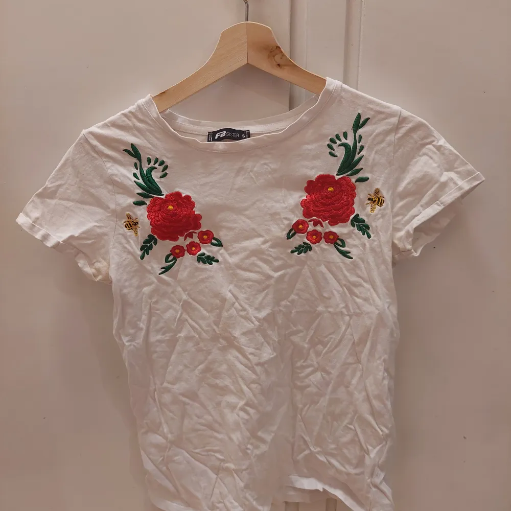 En vit t-shirt med en broderad blomma och humla. Den är i bra skick.  25kr+frakt. T-shirts.